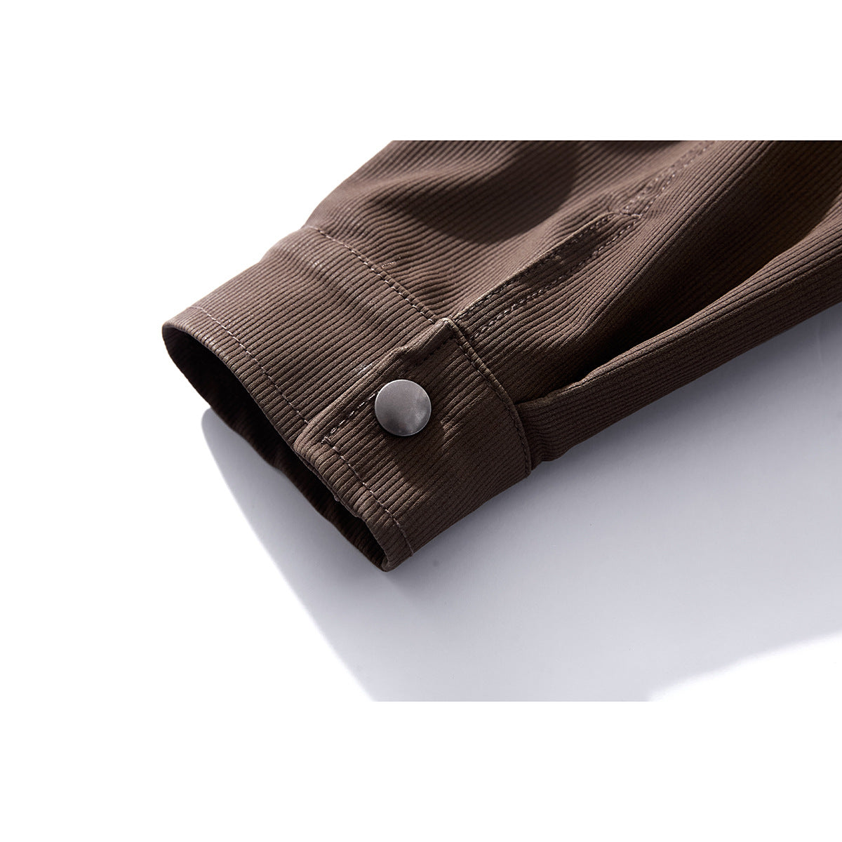 Close-up of a brown jacket sleeve cuff with a silver snap button and stitched seams.