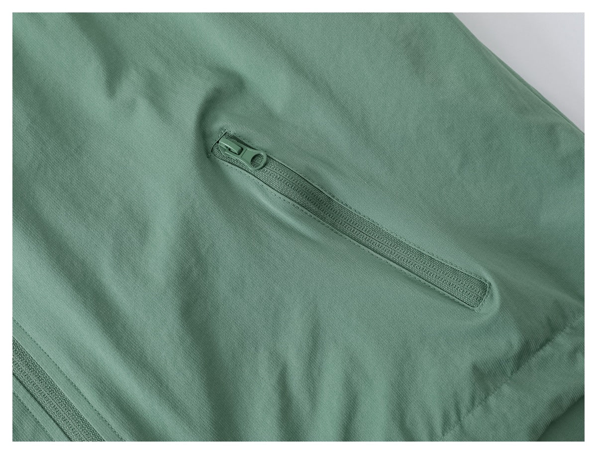 Close-up of a diagonal zip pocket on sage green jacket fabric.