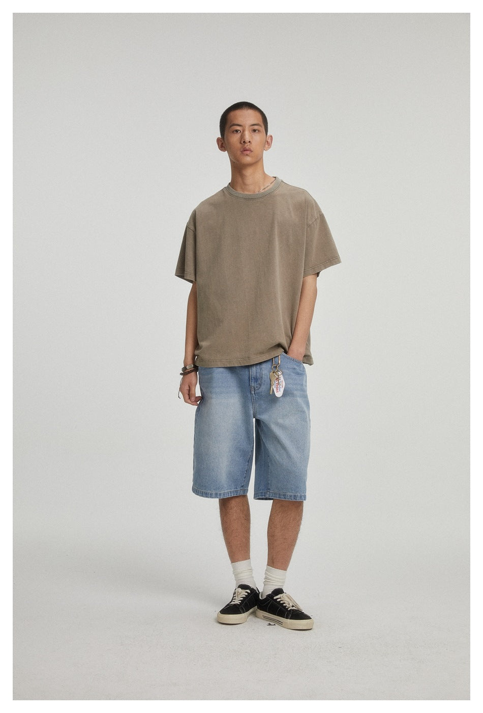 Front view of a model wearing a taupe oversized T-shirt and light blue denim shorts.
