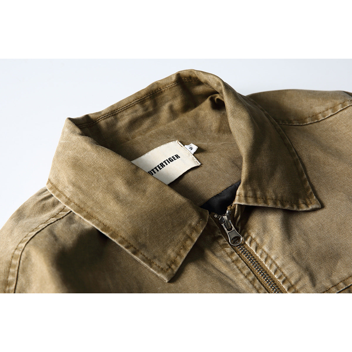 Close-up of a tan-brown jacket collar, zipper, and sewn neck label.