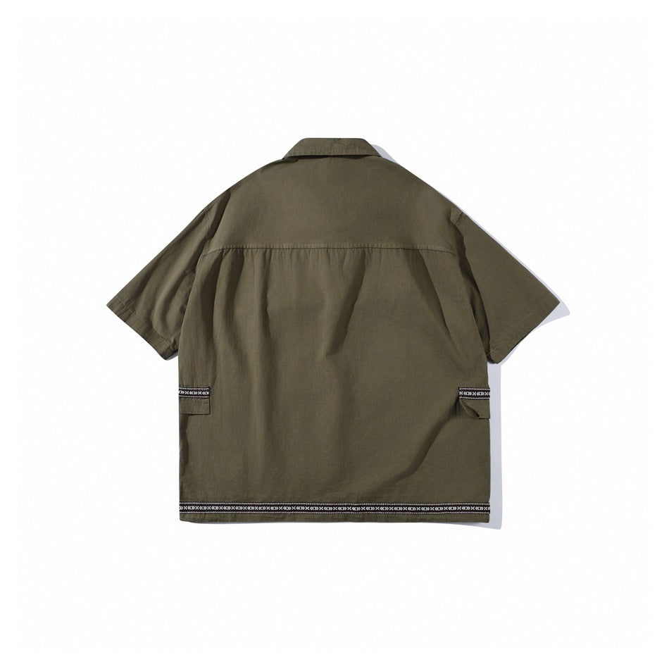 Back view of an olive-green short-sleeve shirt with side pockets and narrow patterned trim at the pocket flaps and hem.