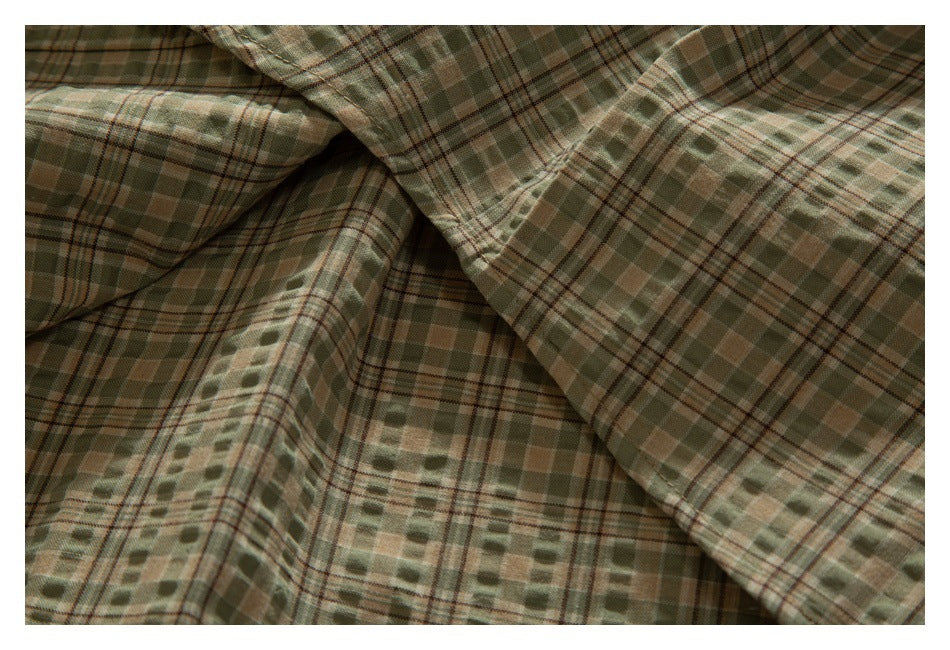 Close-up of folded fabric with a muted olive, tan, and brown plaid pattern.