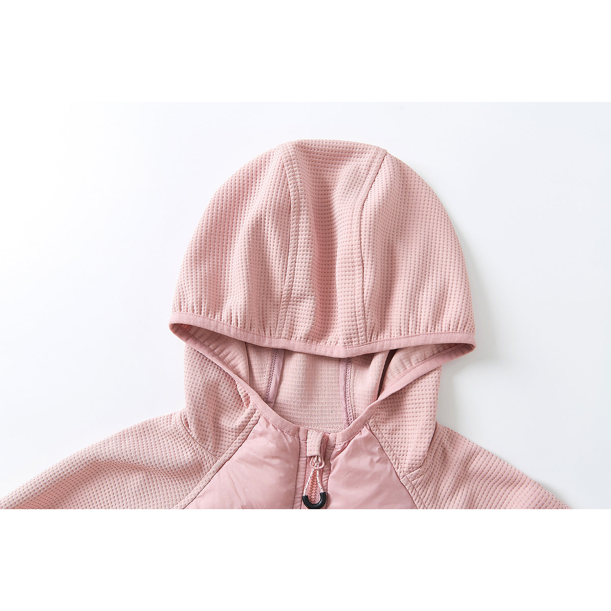 Close-up of the pink hood and upper chest of a jacket, showing textured panels and a front zipper pull.