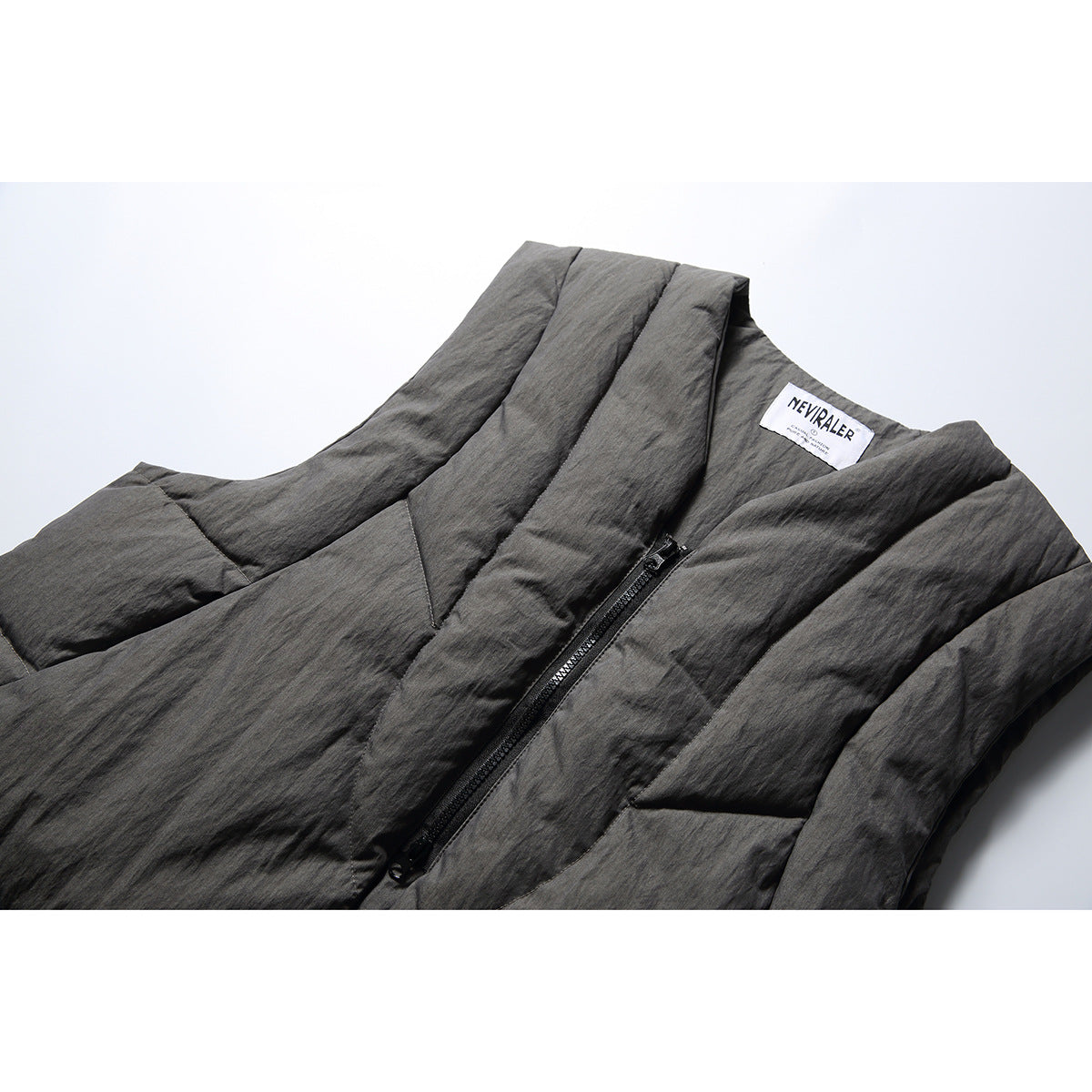 Close-up of a charcoal-gray padded vest's V neckline, sewn label, and black front zipper.