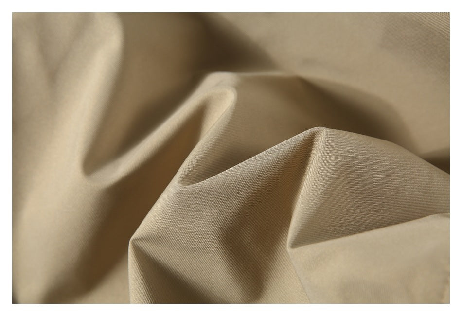 Close-up of beige fabric draped in soft folds, showing its fine woven texture.