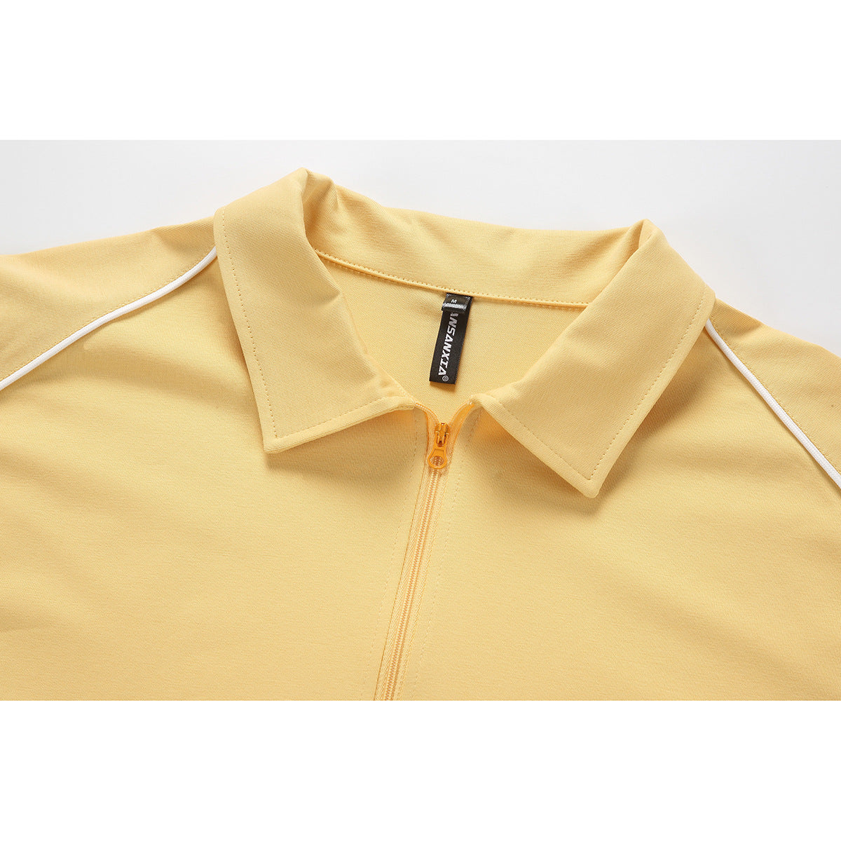 Close-up of a pale yellow polo shirt collar, short zipper, and white shoulder piping.