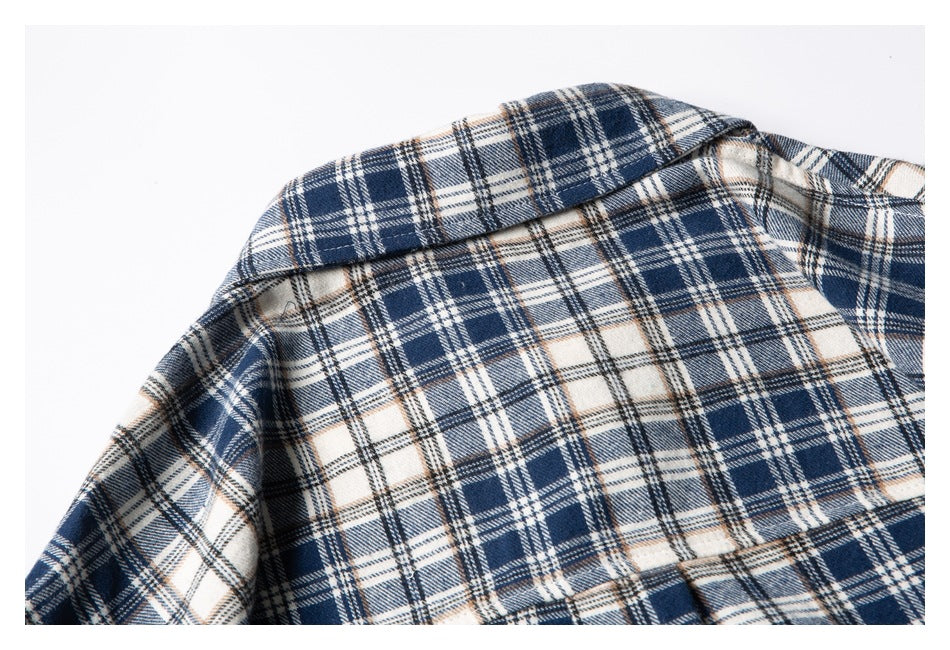 Close-up of the collar and shoulder of a navy, cream, and tan plaid shirt.