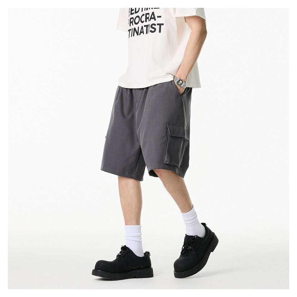 Person walking in gray knee-length cargo shorts with a side flap pocket, white tee, white socks and black shoes