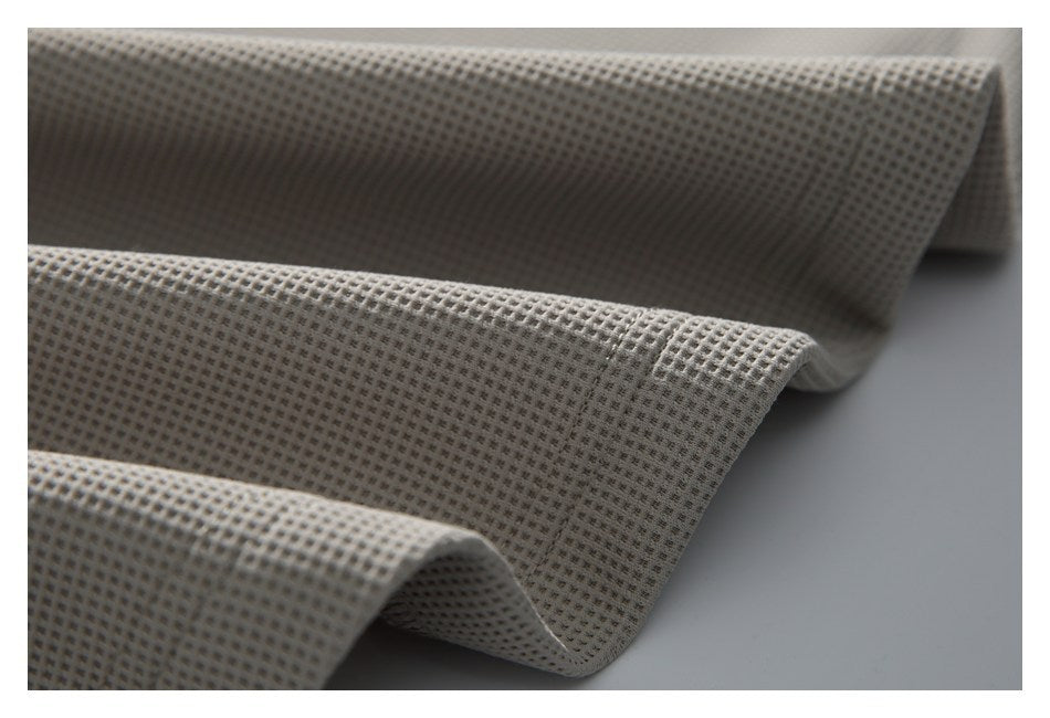Close-up of light gray-beige fabric with a small, evenly spaced waffle-like texture, draped in folds.