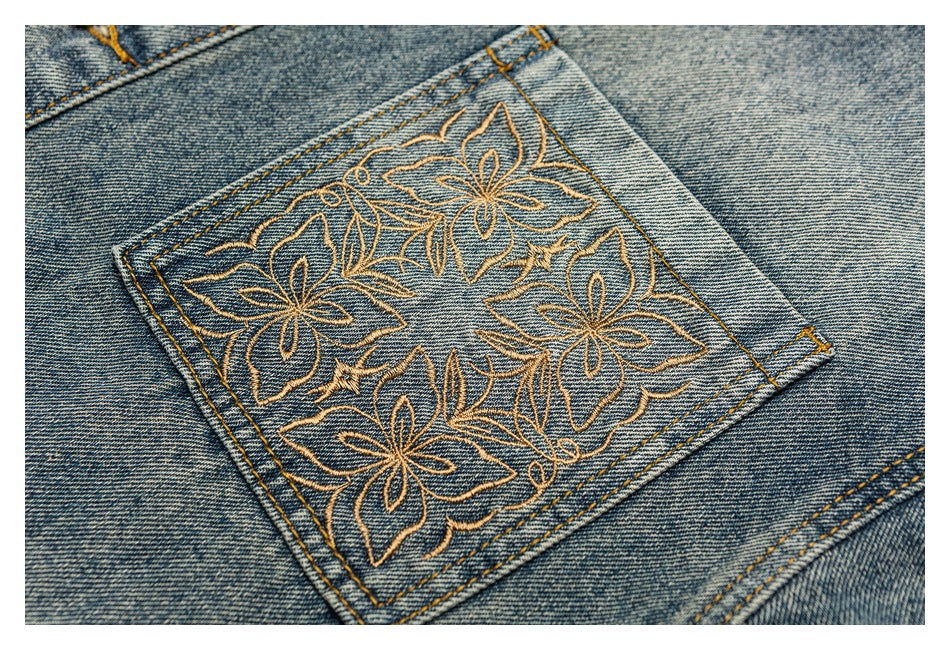 Close-up of a denim pocket with gold floral embroidery and contrasting yellow stitching.