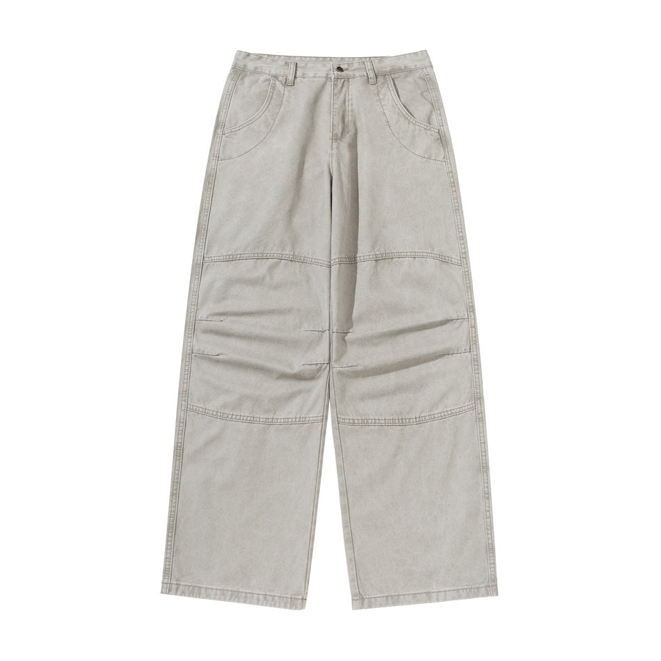 Front view of light gray washed wide-leg pants with knee seams, curved front pockets and button zip fly