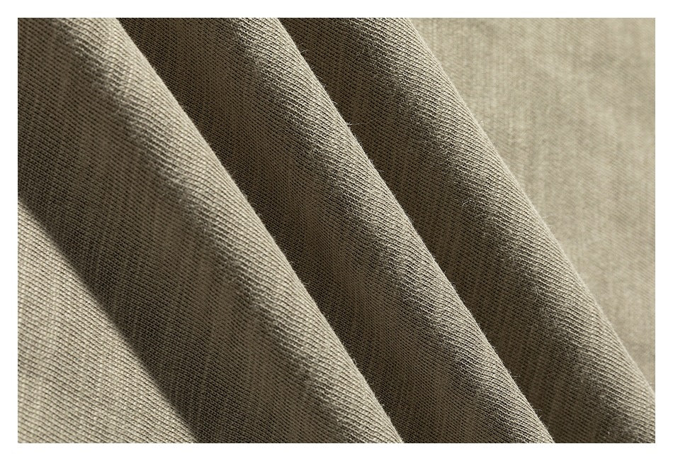 Close-up of beige-gray knit fabric draped in folds, showing its texture.