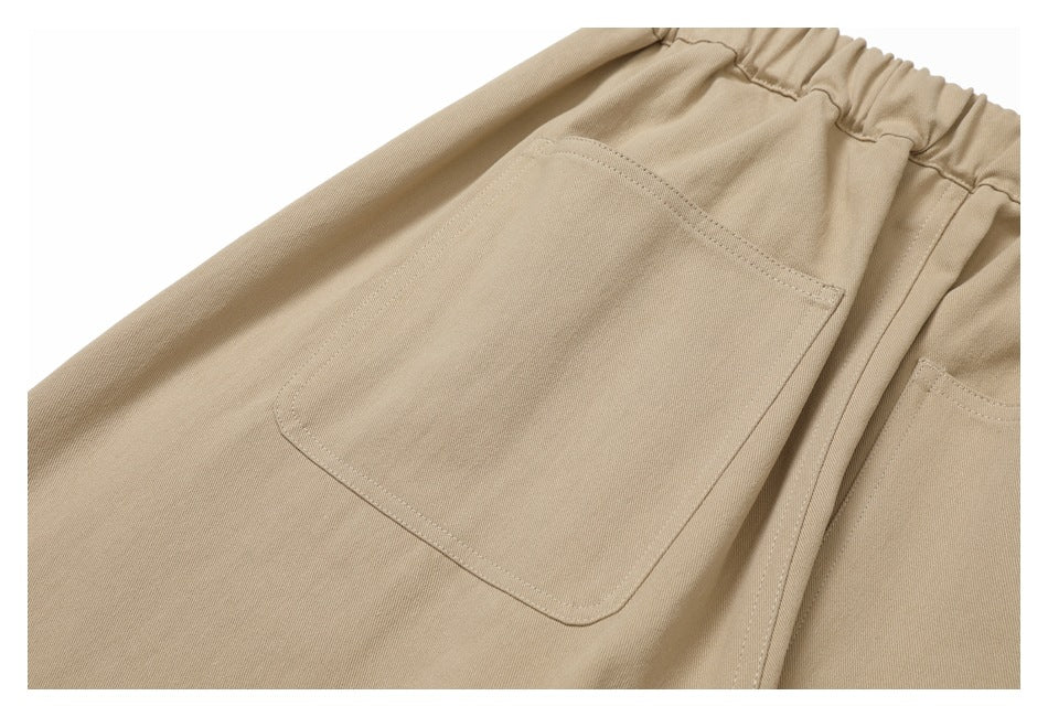 Close-up of a large stitched patch pocket on beige pants.