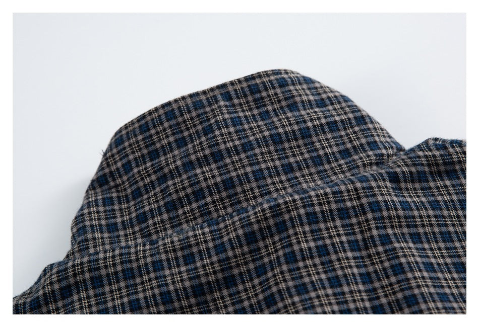 Close-up of a curved section of dark blue, beige, and black plaid fabric.