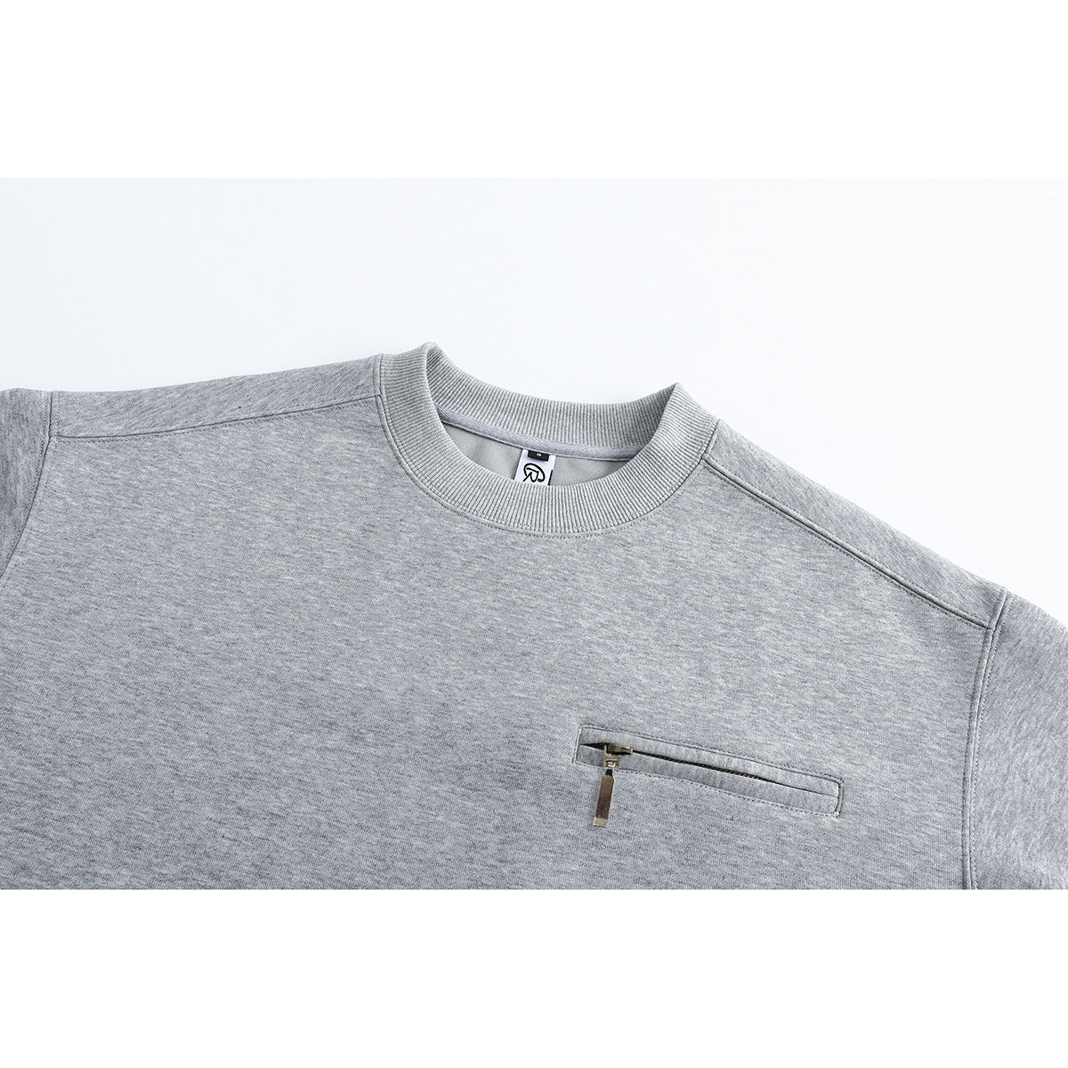 Close-up of a heather gray crewneck sweatshirt showing its ribbed collar and horizontal zip chest pocket.