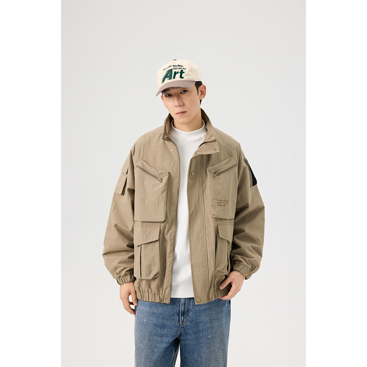 Front view of a model wearing an open khaki utility jacket with multiple pockets over a white shirt.