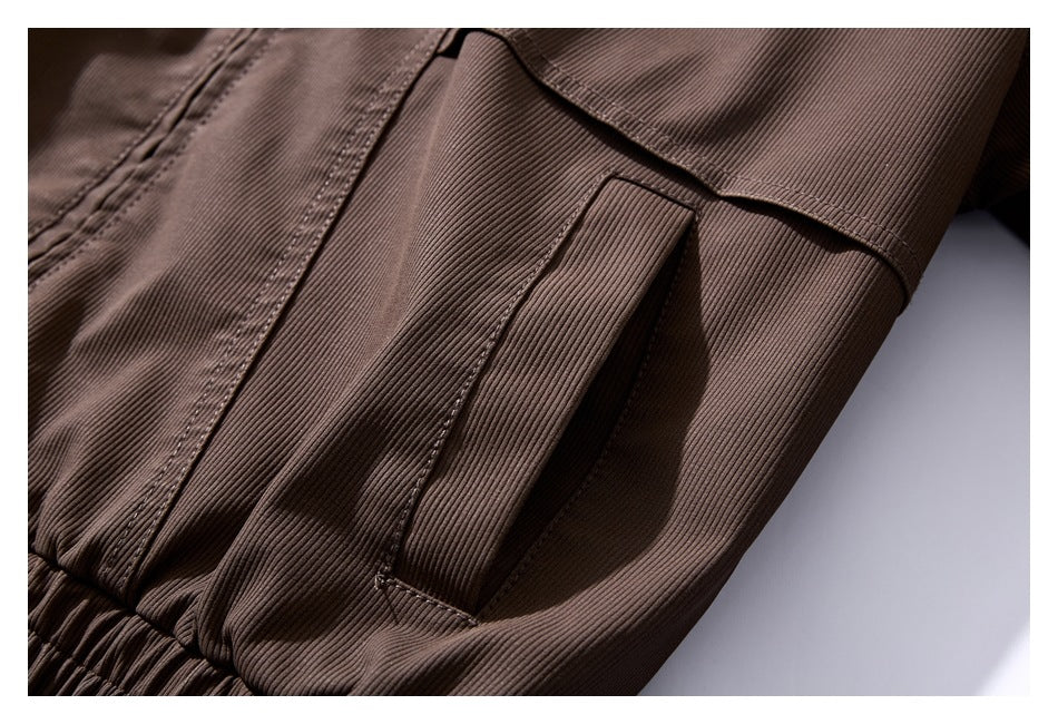 Close-up of a brown ribbed jacket showing a narrow vertical pocket opening and gathered hem.