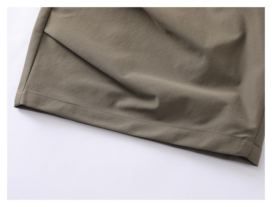 Close-up of taupe trouser fabric, diagonal panel and stitched lower hem.
