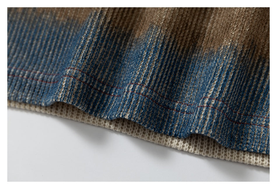 Close-up of a striped blue and brown knit garment edge with red stitching and a cream ribbed underside.