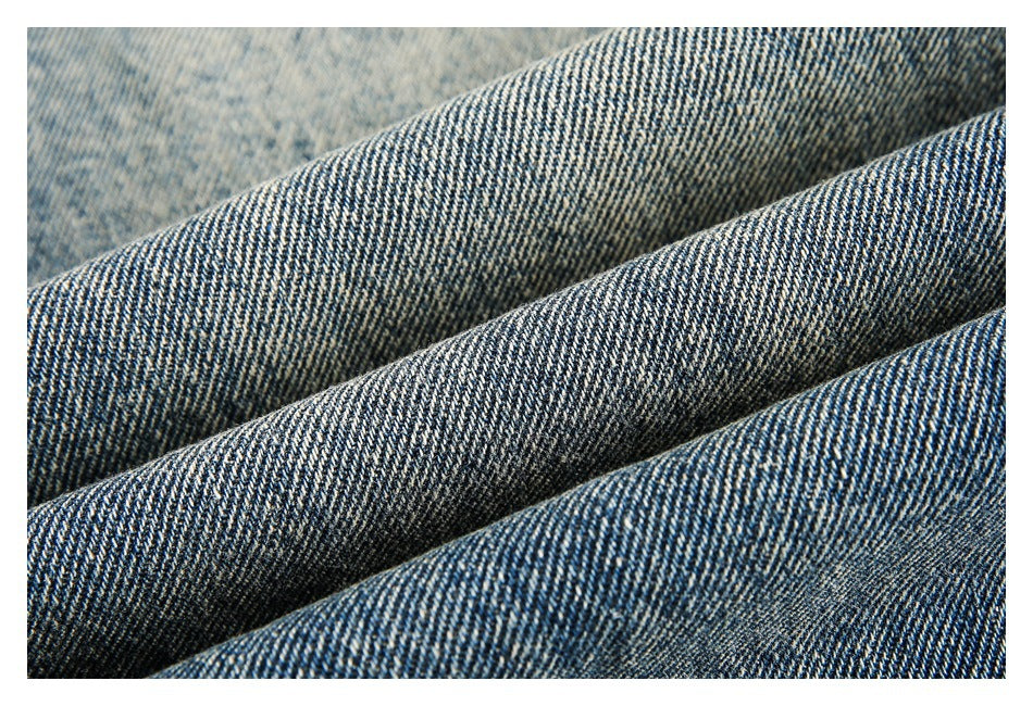 Macro view of blue denim fabric folded to show its diagonal weave and faded surface.