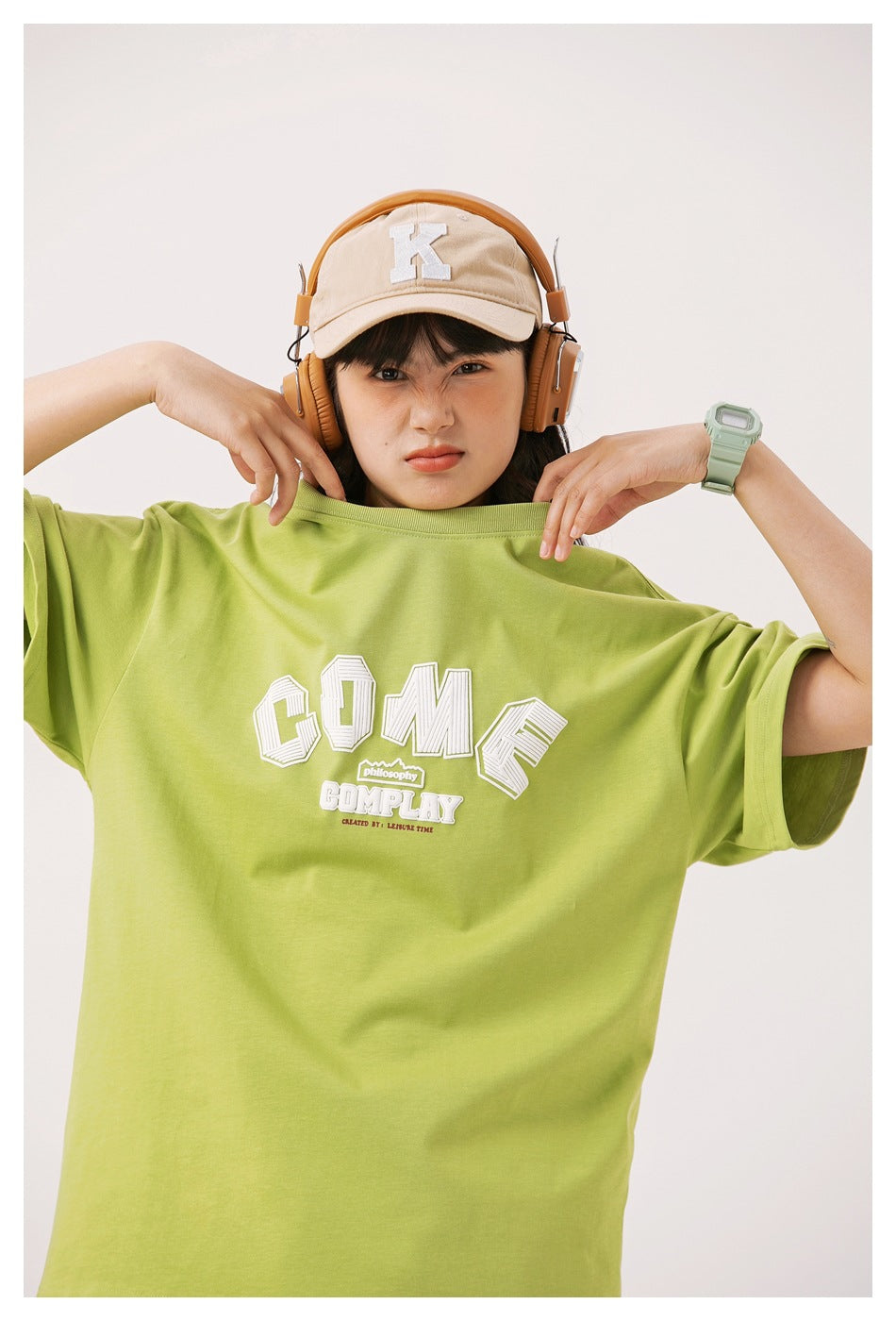 Close view of a lime green T-shirt on a model, showing its white chest graphic, crew neckline, and wide sleeves.