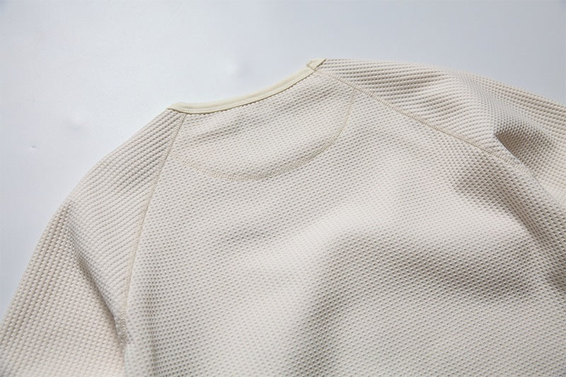 Close-up of the cream waffle-knit shirt's back neckline and raglan shoulder seams.