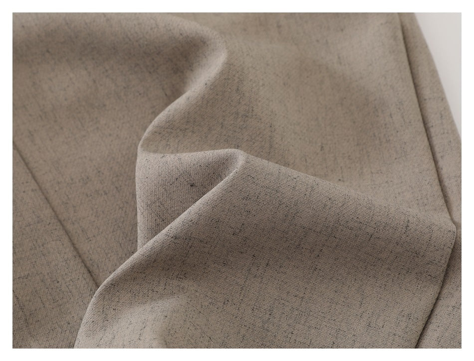 Close-up showing the mottled beige-gray trouser fabric folded to reveal its drape and surface texture.