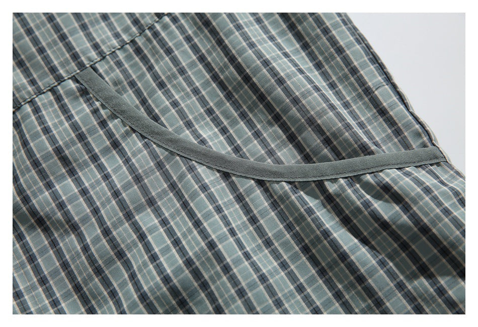 Close-up of a curved dark trim detail across gray-green plaid jacket fabric.