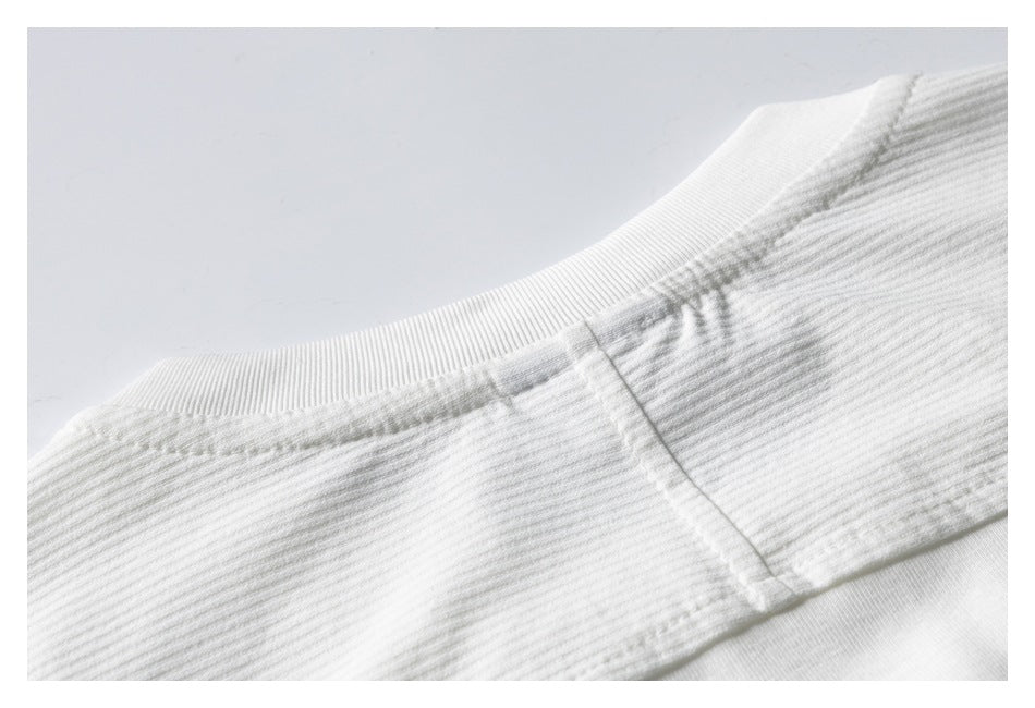 Close-up of the ribbed crew neckline and shoulder seam of a white garment.