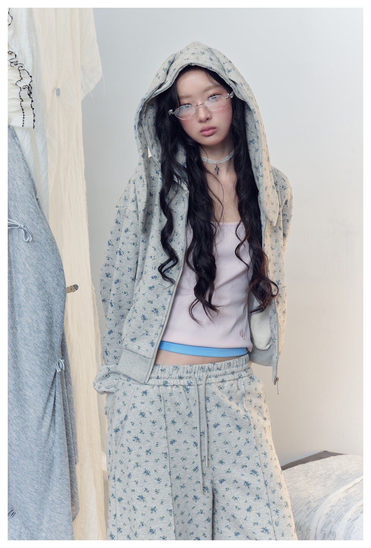 Close view of a model wearing a gray-blue floral hooded zip jacket and matching pants.