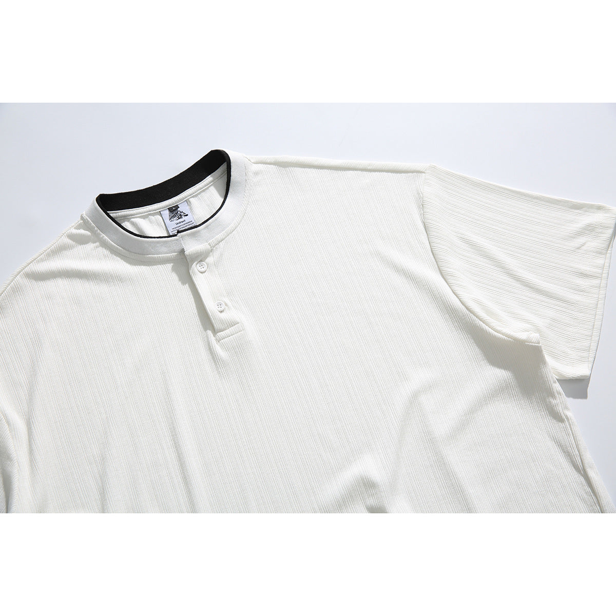 Close view of an off-white ribbed short-sleeve shirt with a band collar and two-button placket.