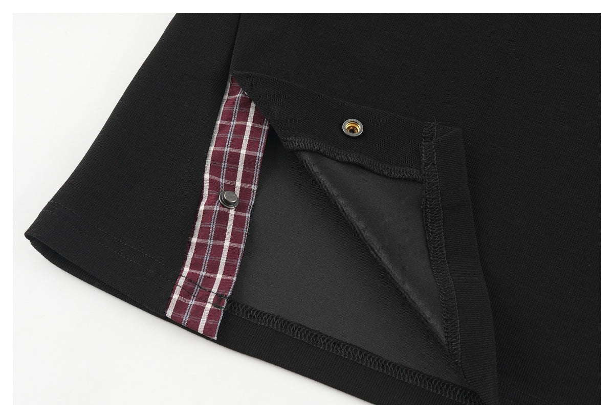 Inside view of a black garment showing a burgundy plaid inset and snap fastener.