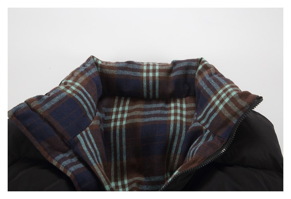 Close-up of a black jacket with a wide brown, navy, and teal plaid-lined collar.