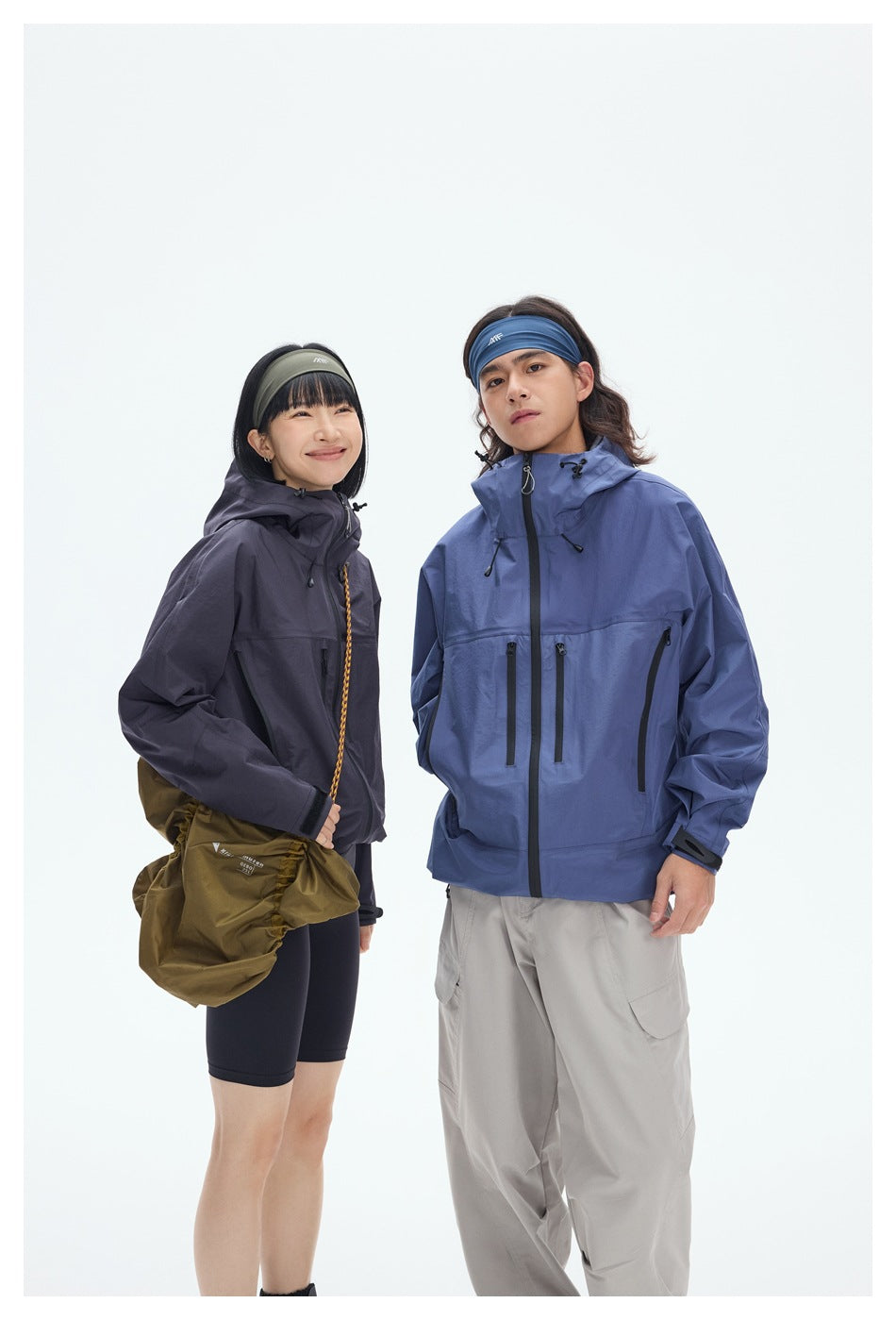 Closer view of two models wearing charcoal and blue hooded jackets with front zippers, adjustable hoods, and zip pockets.