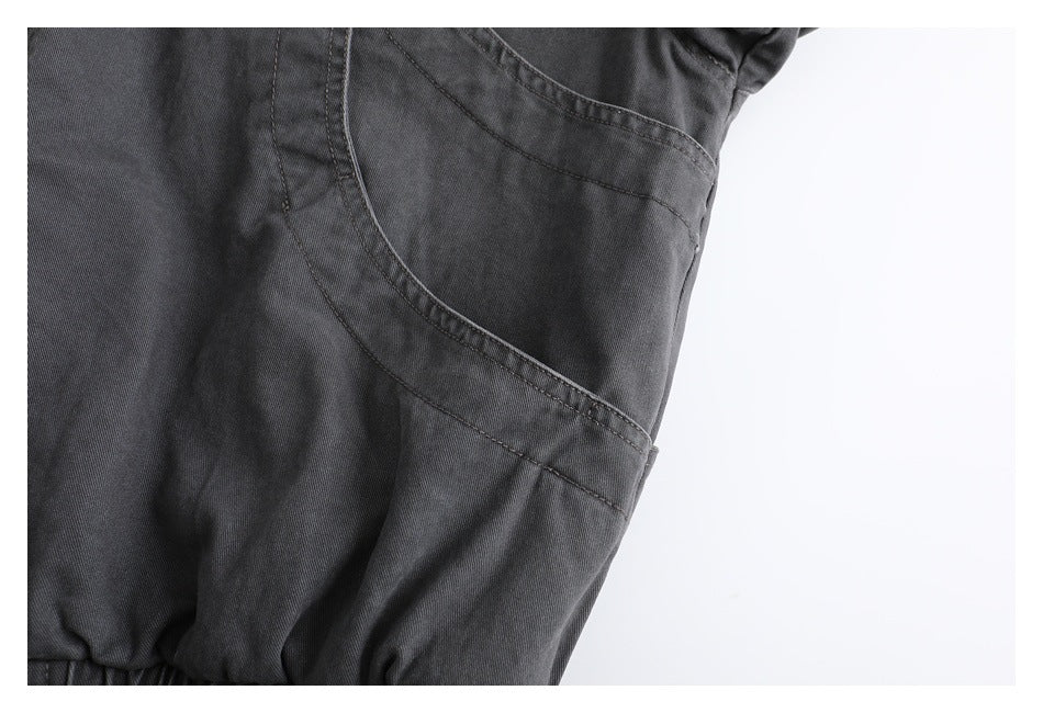 Close-up of a charcoal garment showing a curved, stitched seam and gathered edge.