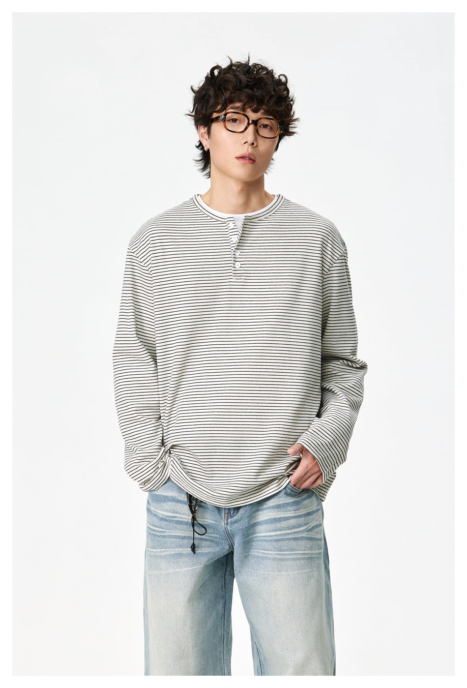 Model wearing an ivory thin-striped long-sleeve henley with light blue jeans.
