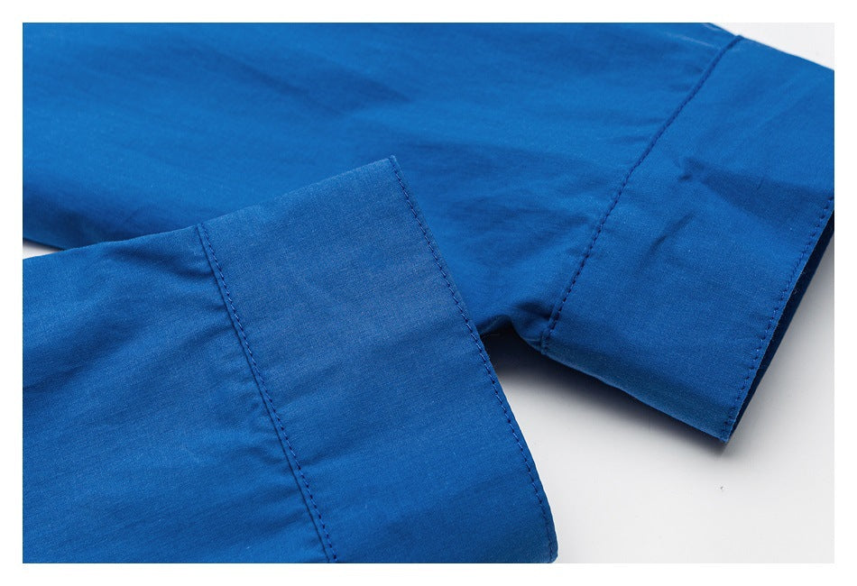 Close-up of a bright blue shirt sleeve and wide cuff with visible stitching.