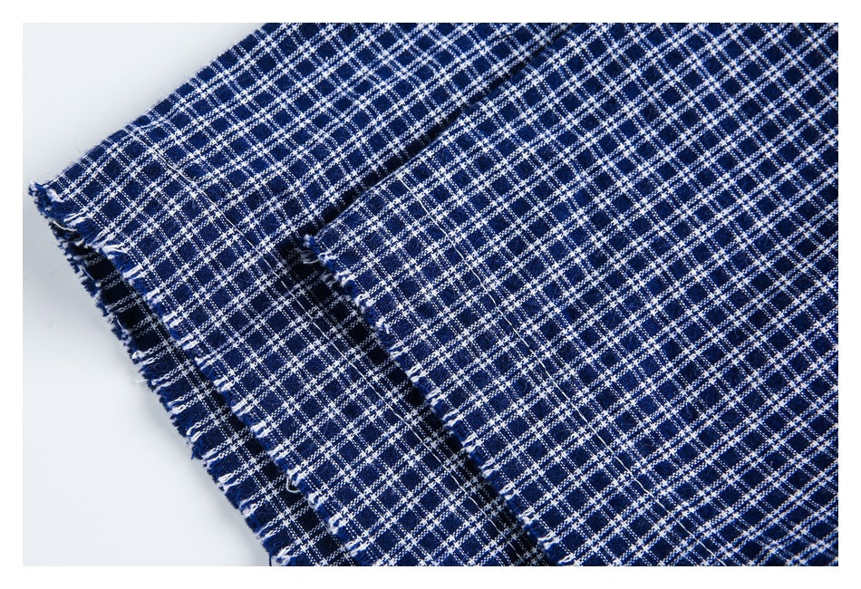 Close-up of layered navy and white plaid fabric with fringed edges.
