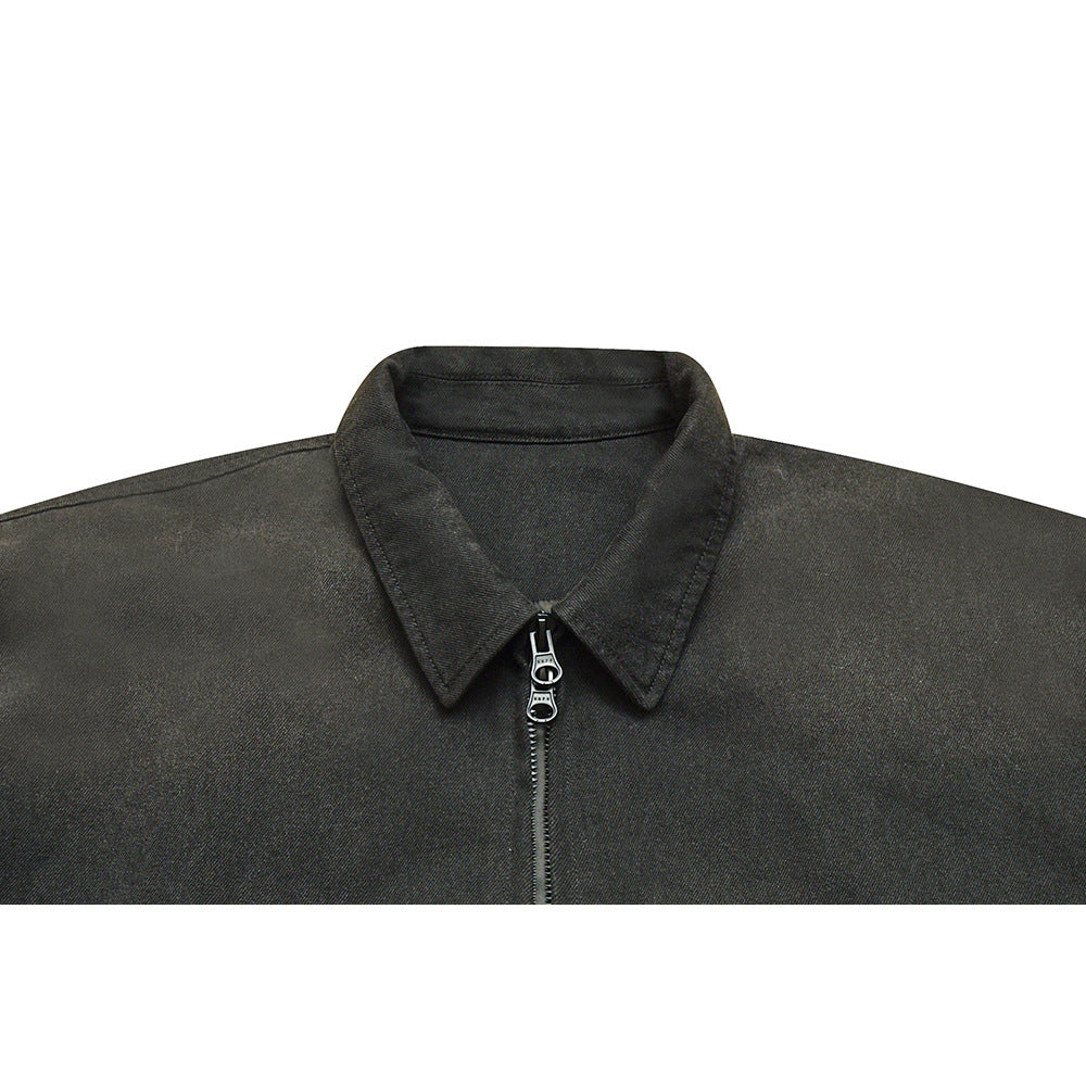 Close-up of a charcoal jacket's pointed collar and front zipper with a decorative metal pull.