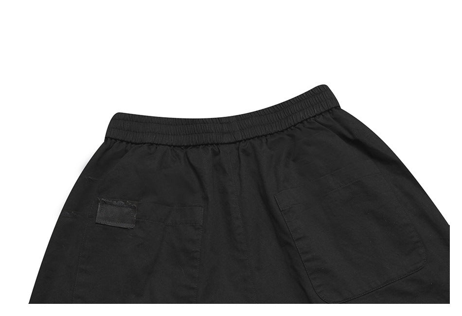 Close-up of the back of black bottoms, showing an elastic waistband and two large patch pockets.