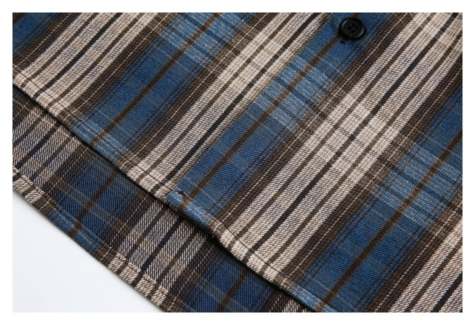 Close-up of the shirt's plaid fabric, black button, and stitched edge.