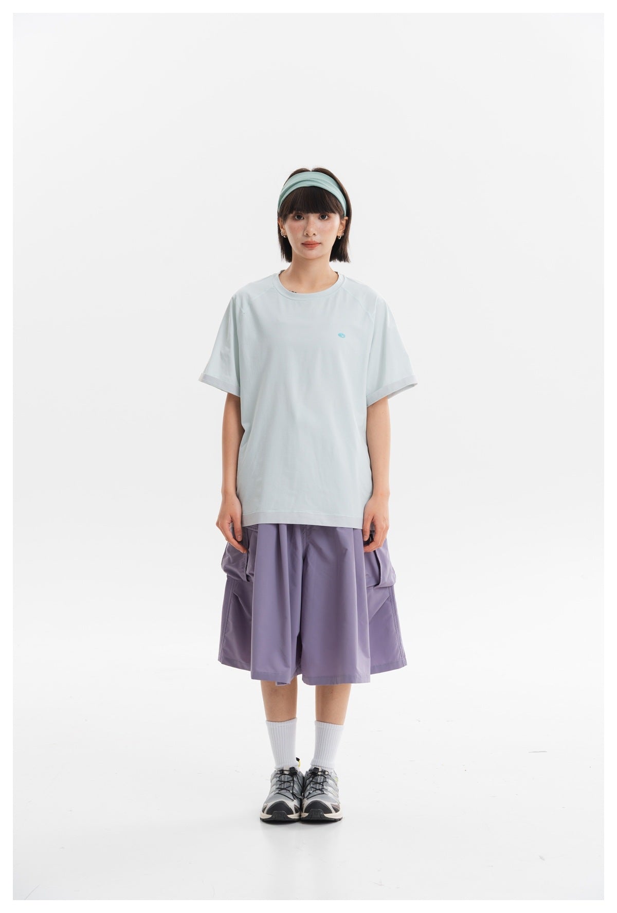 Model wearing a pale blue short-sleeve T-shirt and lavender wide cargo shorts.