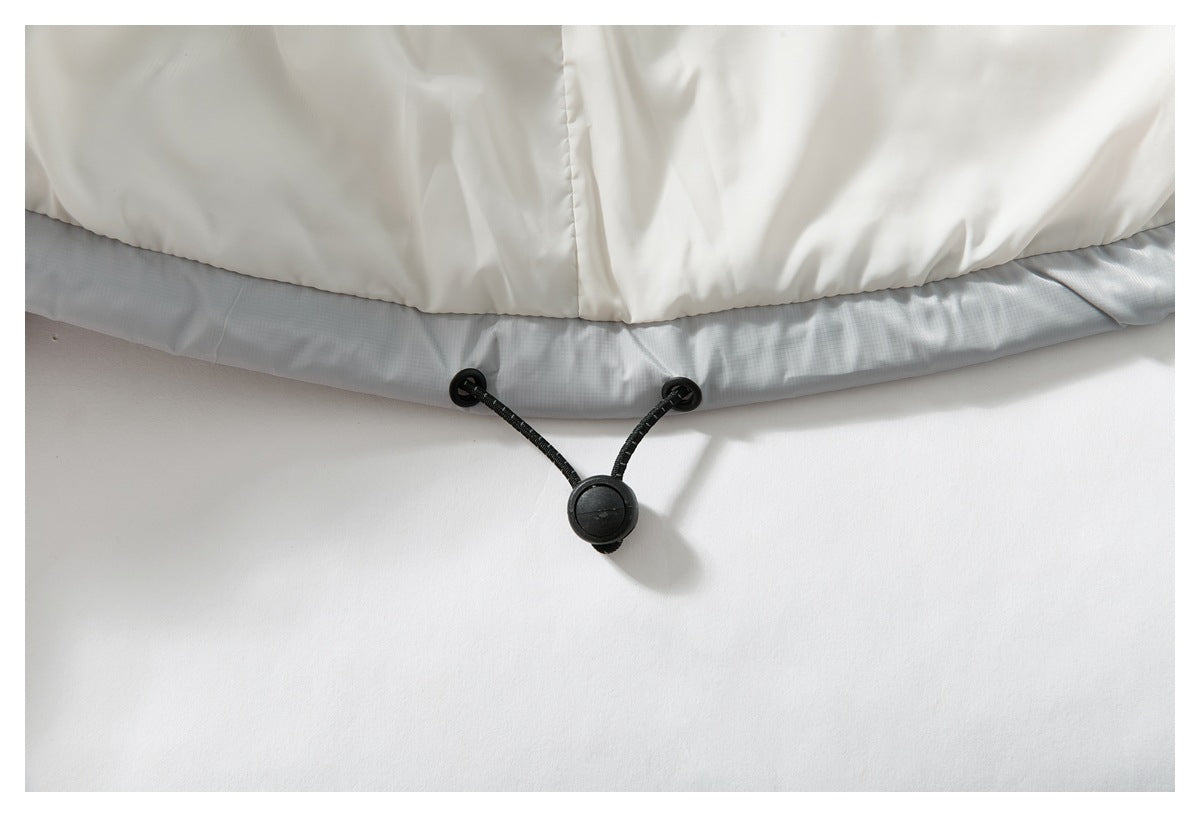 Close-up of a black adjustable drawcord and toggle at the hem of a pale jacket.