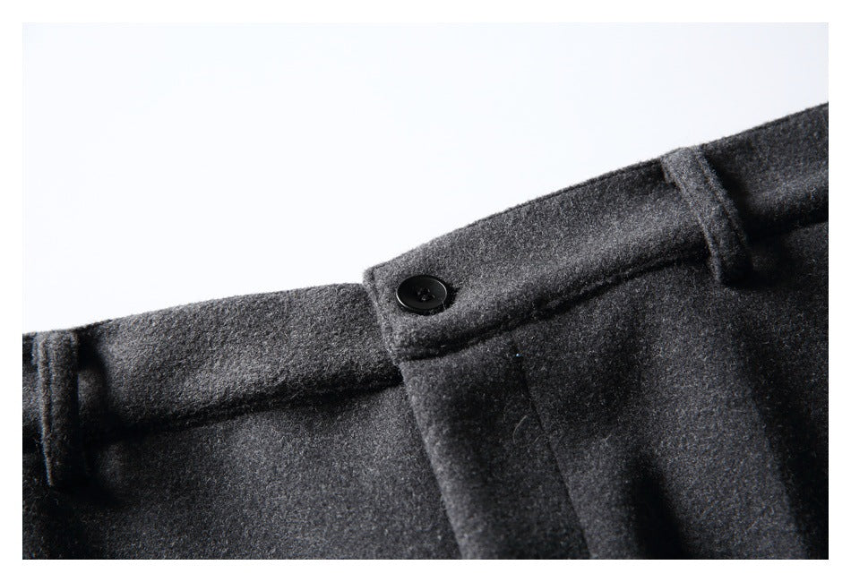 Close-up of charcoal gray trousers showing a black waistband button, belt loops, and front seam.