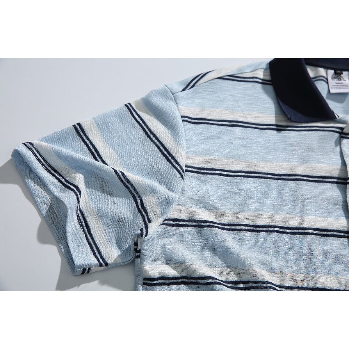 Close-up of the polo's striped short sleeve, shoulder seam, and navy collar.