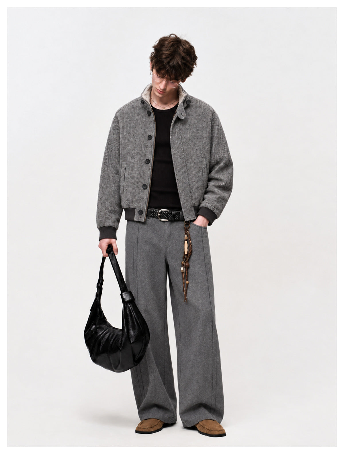 Model wearing a gray textured jacket and matching wide-leg trousers with a black top and belt.