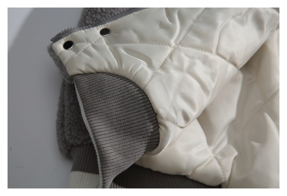 Close-up of the cream quilted sleeve, gray ribbed cuff, and two dark snaps.