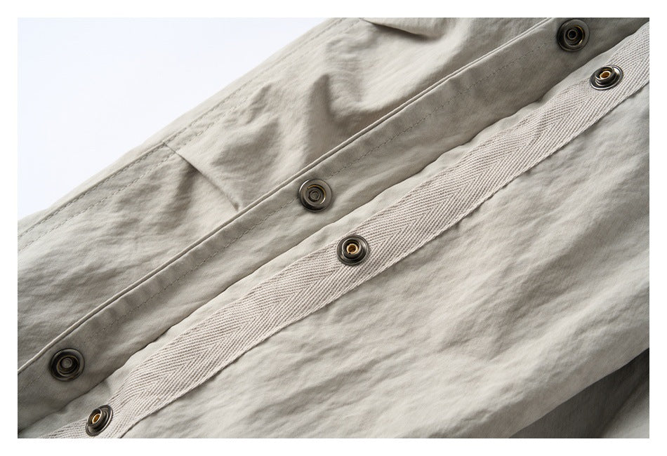 Close-up of the jacket’s light beige-gray snap-fastened front placket and inner facing.