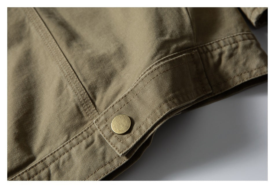 Close-up of an olive-khaki garment seam with a round brass-colored snap fastener.