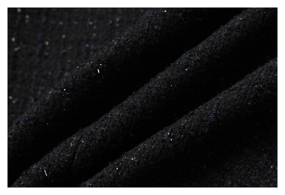Macro view of the garment's black textured fabric with subtle blue flecks.